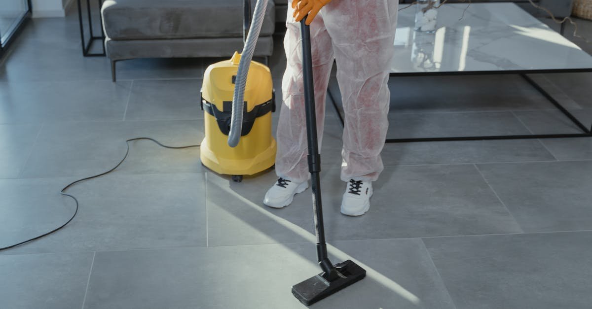 A professional cleaner in protective gear vacuuming the floor in a modern living room.